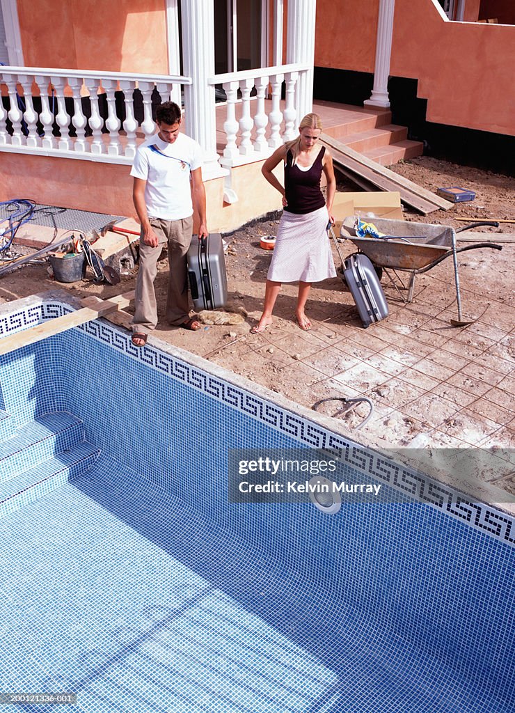 Couple by empty pool outside apartment building under construction