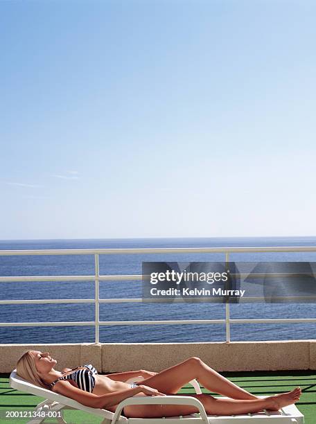 young woman relaxing on sun lounger on terrace overlooking sea - hot women on boats ストックフォトと画像