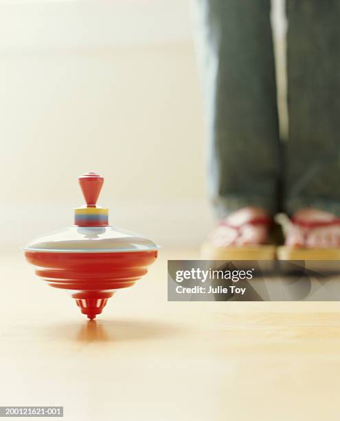 top spinning on floor, woman standing in background - spinning top stock pictures, royalty-free photos & images