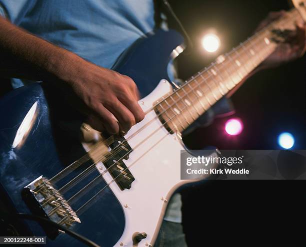 mature man playing electric guitar, mid section - bass guitar stock pictures, royalty-free photos & images