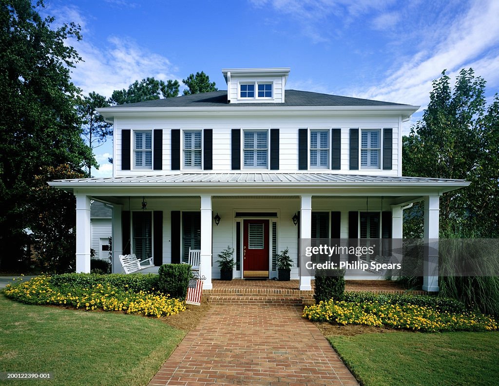 White wooden house, flowers blooming around front porch