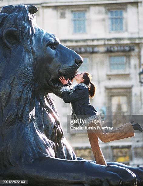 young woman kissing lion statue, side view - kissing statue stock pictures, royalty-free photos & images