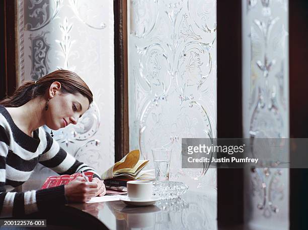 Young woman writing postcard in pub