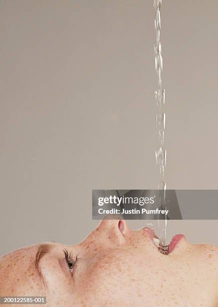 young woman catching water in mouth, profile - women open mouth stock pictures, royalty-free photos & images