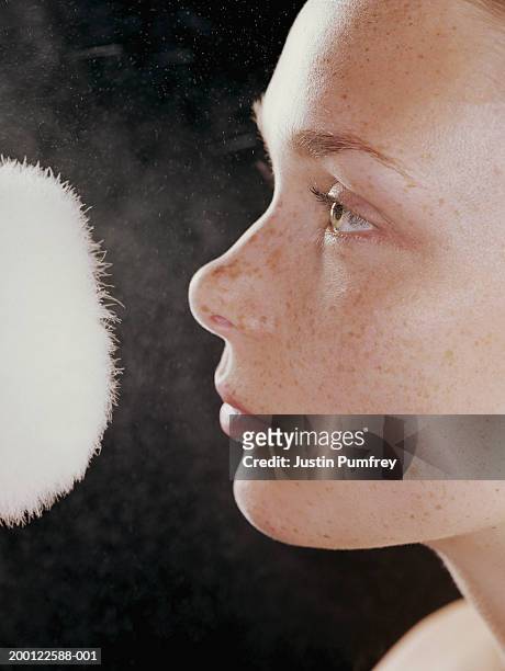 young woman with powder puff in front of face, close-up, side view - powder puff stock pictures, royalty-free photos & images
