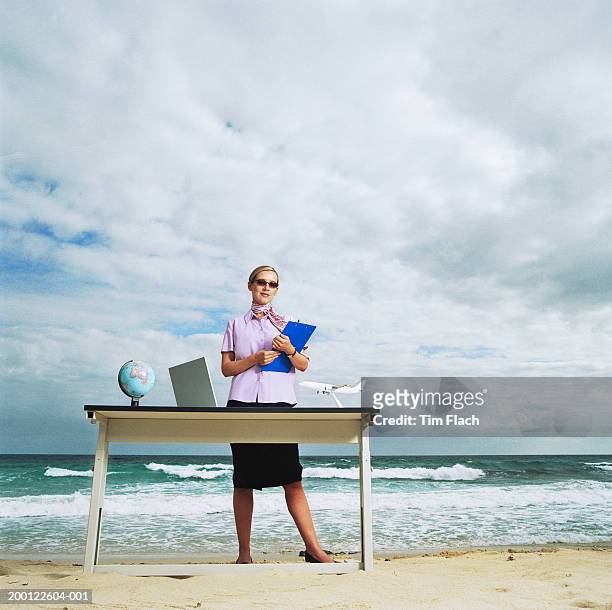 female tour guide standing behind desk on beach, portrait - tim flach stock-fotos und bilder