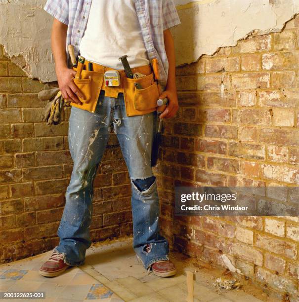 man wearing tool belt beside partially rendered wall, low section - ripped jeans stock pictures, royalty-free photos & images