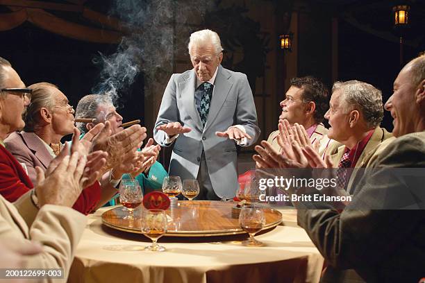 mature businessmen at table, one standing gesturing with hands - mafia stock-fotos und bilder