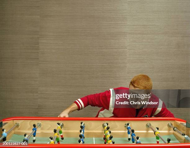 young man bending to look at table football game - totó - fotografias e filmes do acervo