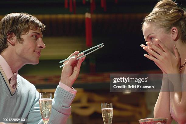 couple in restaurant, man proposing with ring held in chopsticks - man proposing indoor stock-fotos und bilder