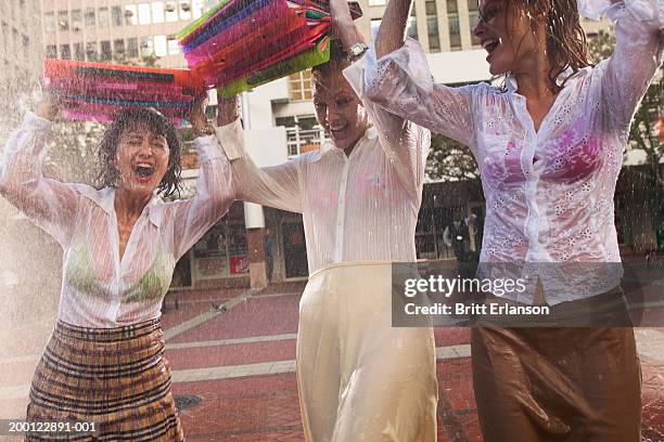 three women in rain holding files above heads - durchnässt stock-fotos und bilder