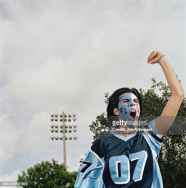 young male sports fan with painted face, cheering and pumping fist - face paint stock pictures, royalty-free photos & images