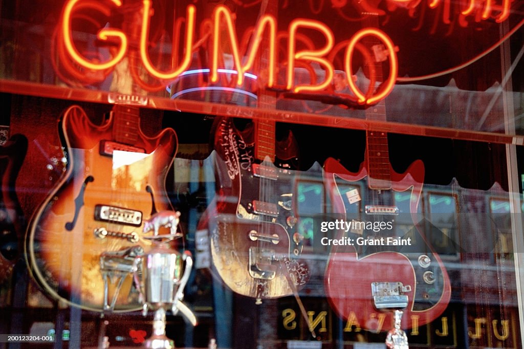 Stores reflected in guitar shop window with neon sign
