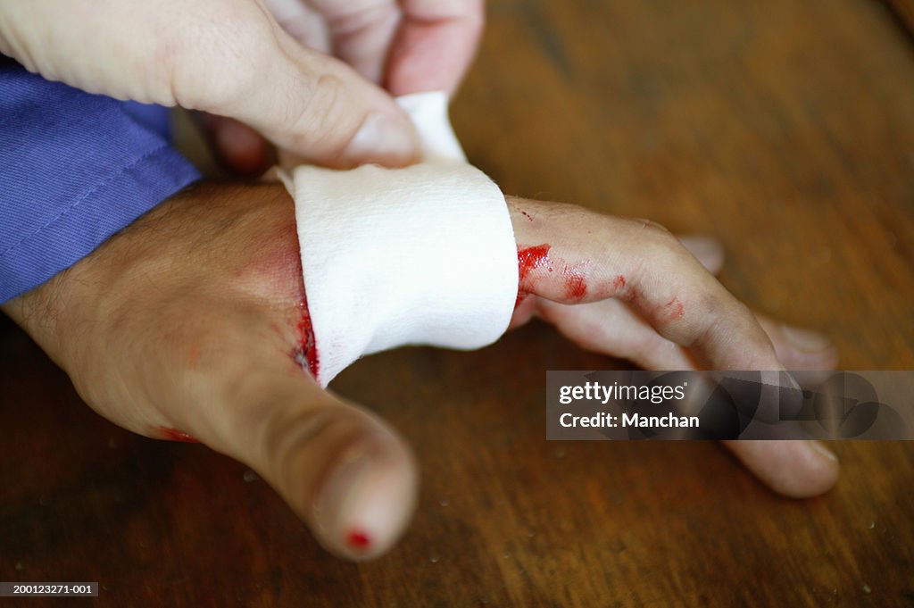 Woman applying dressing to man's wounded hand, close-up
