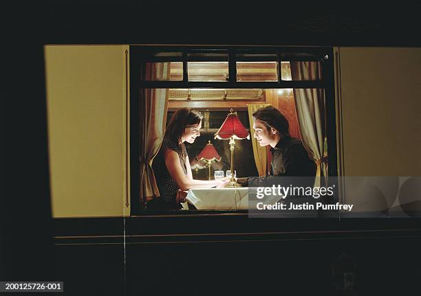 young couple at table aboard train, exterior view, night - date night romance stock-fotos und bilder