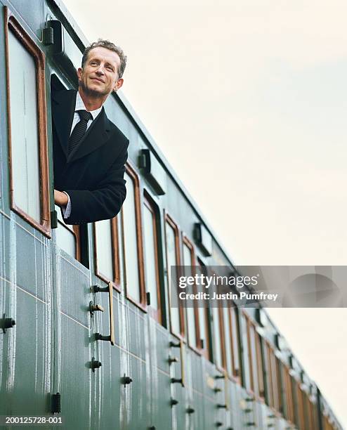 businessman leaning out of train window, low angle view - lean stockfoto's en -beelden