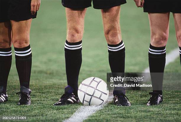 referees lined up on field near soccer ball, low section - referee stockfoto's en -beelden
