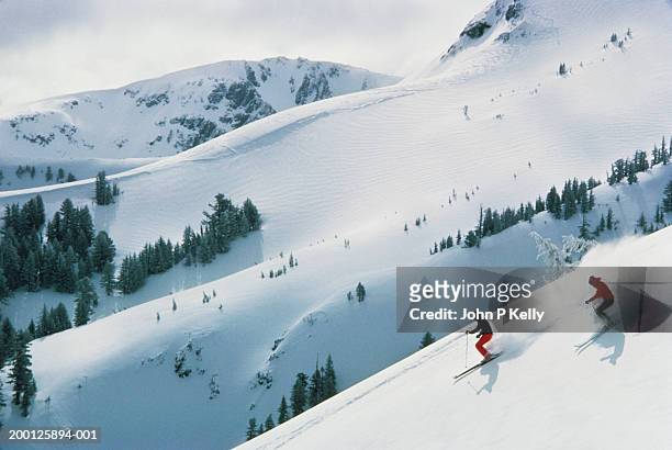 two men skiing down mountain - ski hill stock pictures, royalty-free photos & images