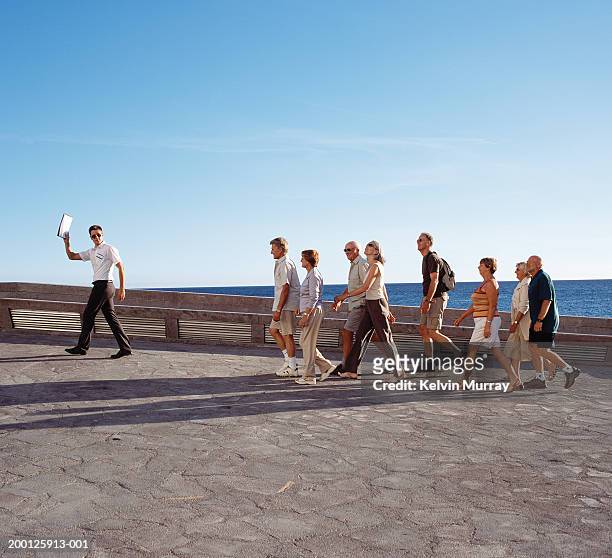 group of tourists following male tour guide, outdoors - guide photos et images de collection