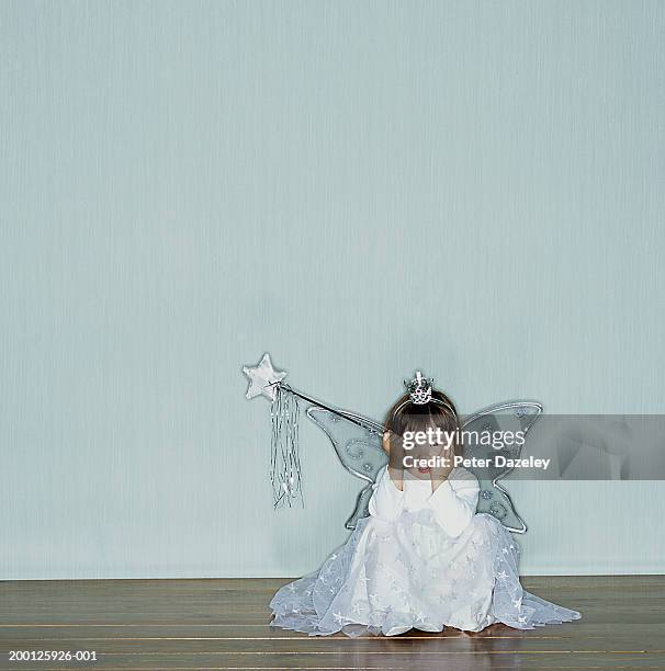 girl (2-4) wearing angel costume sitting on floor, head in hands - fairy costume ストックフ��ォトと画像