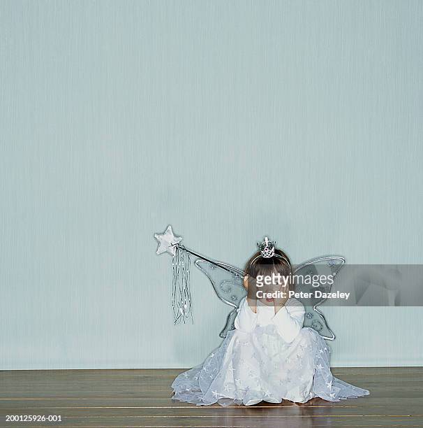 girl (2-4) wearing angel costume sitting on floor, head in hands - child christmas costume stock pictures, royalty-free photos & images