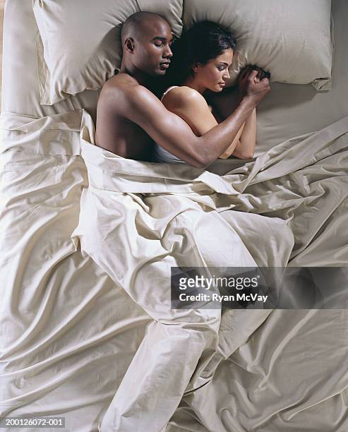 young man and young woman sleeping next to each other, overhead view - pareja abrazados cama fotografías e imágenes de stock