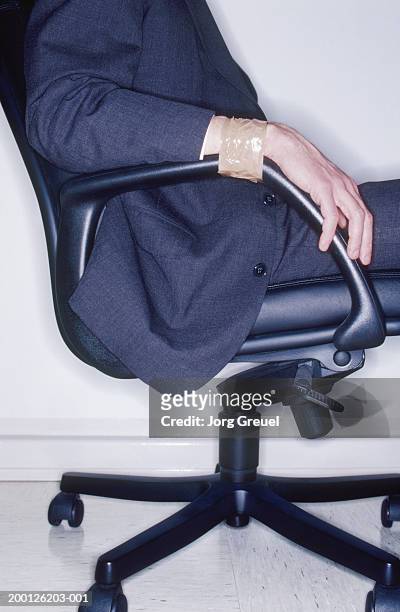 businessman, wrists taped to arms of chair, side view, mid section - man tied to chair stockfoto's en -beelden