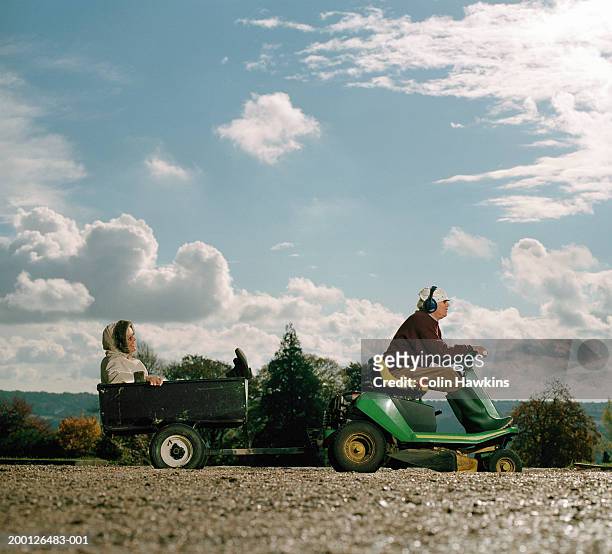 mature man driving garden tractor with mature woman in trailer - riding lawnmower stock pictures, royalty-free photos & images
