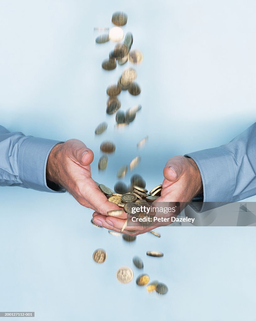 Man cupping hands under stream of falling one pound coins