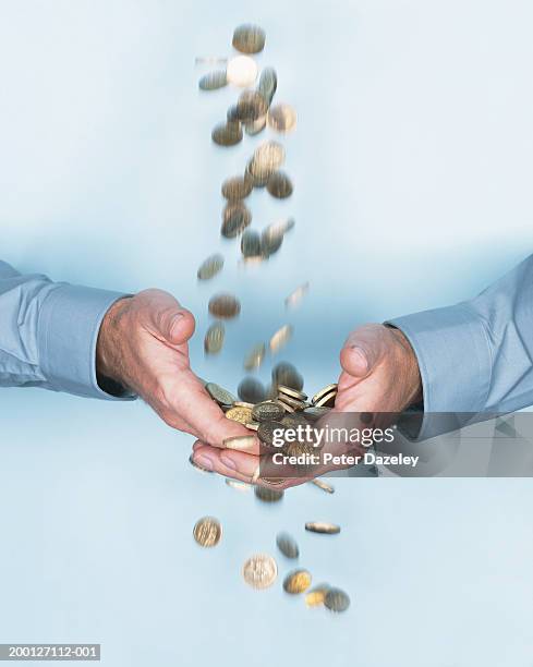 man cupping hands under stream of falling one pound coins - catching money stock pictures, royalty-free photos & images