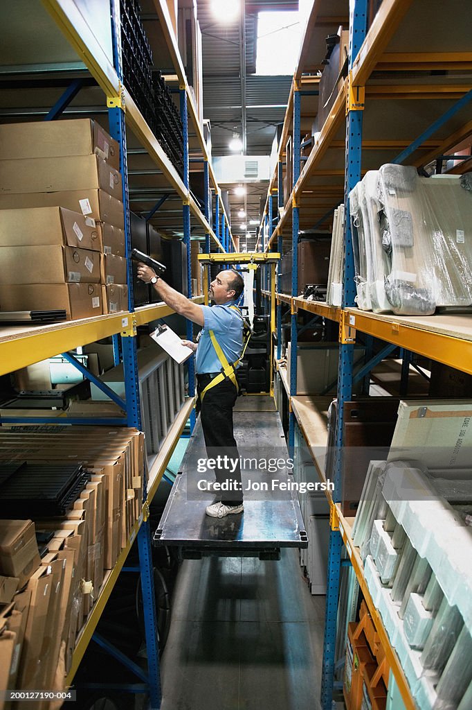 Man on lift scanning boxes in warehouse