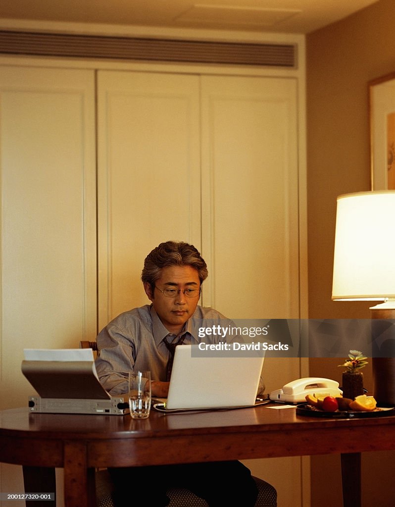 Mature businessman using laptop in hotel room