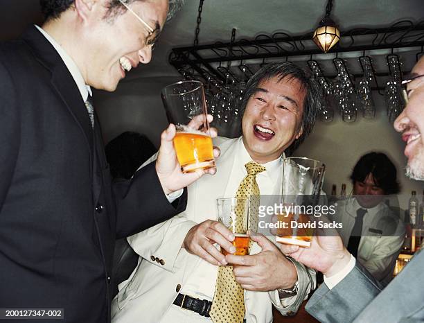 mature businessmen laughing in bar - beer bar stock-fotos und bilder