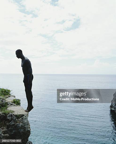 jamaica, negril, man standing on edge of cliff, side view - cliff edge stock-fotos und bilder