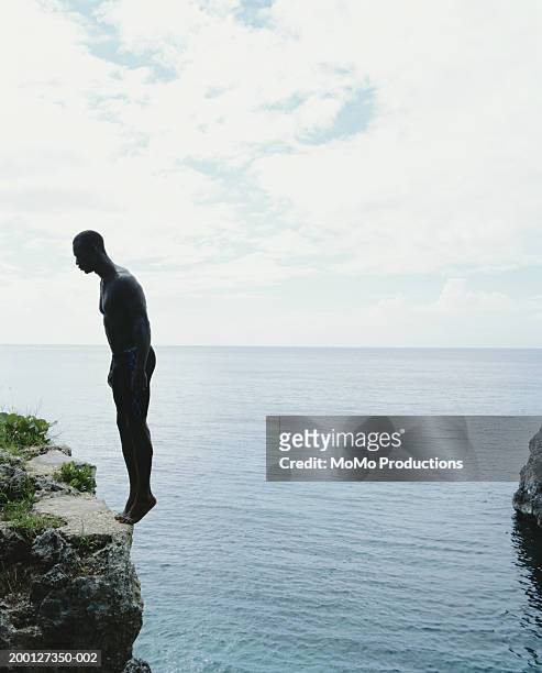 jamaica, negril, man standing on edge of cliff, side view - cliff dive stock pictures, royalty-free photos & images