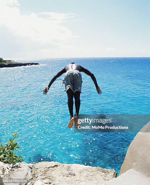 jamaica, negril, man diving off cliff, into ocean, rear view - jamaican ethnicity ストックフォトと画像