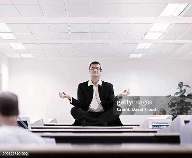 businessman meditating on office desk - businessman meditating stock pictures, royalty-free photos & images