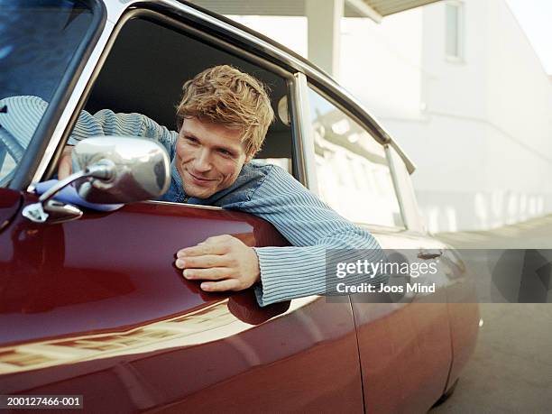 man leaning out car window looking in wing mirror, close-up - presumir fotografías e imágenes de stock