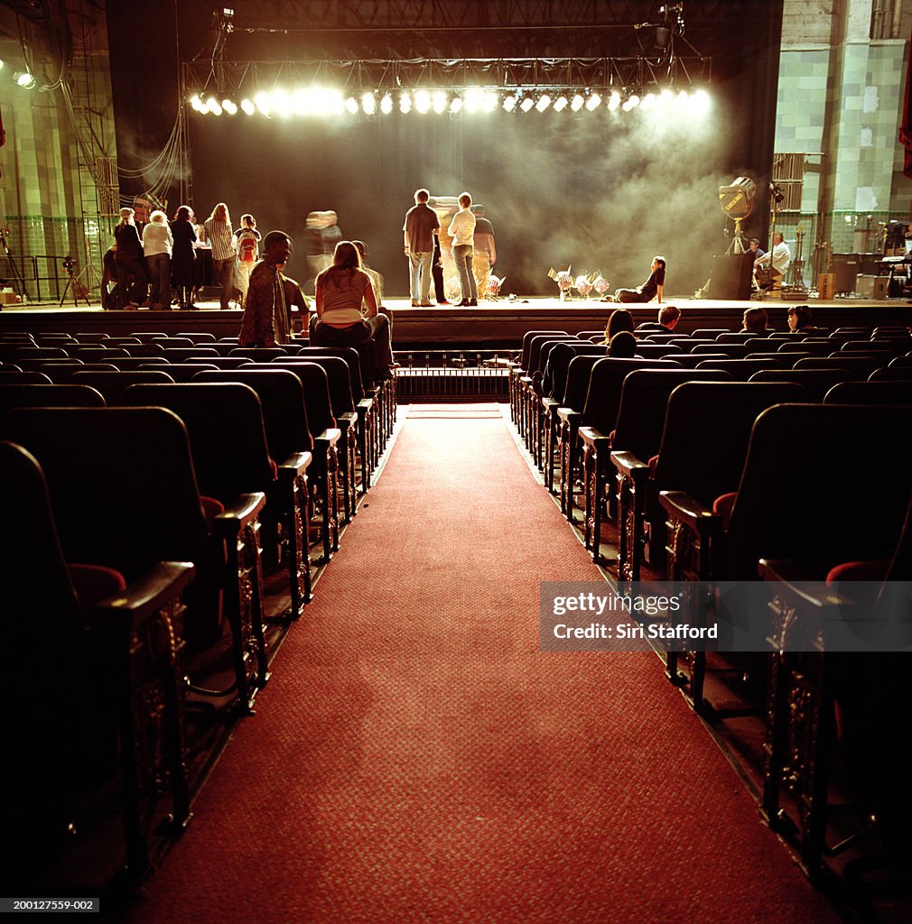 People on stage in empty theatre, waiting for event