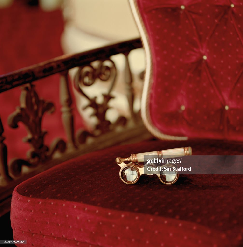 Opera glasses sitting on red chair in theater, close-up