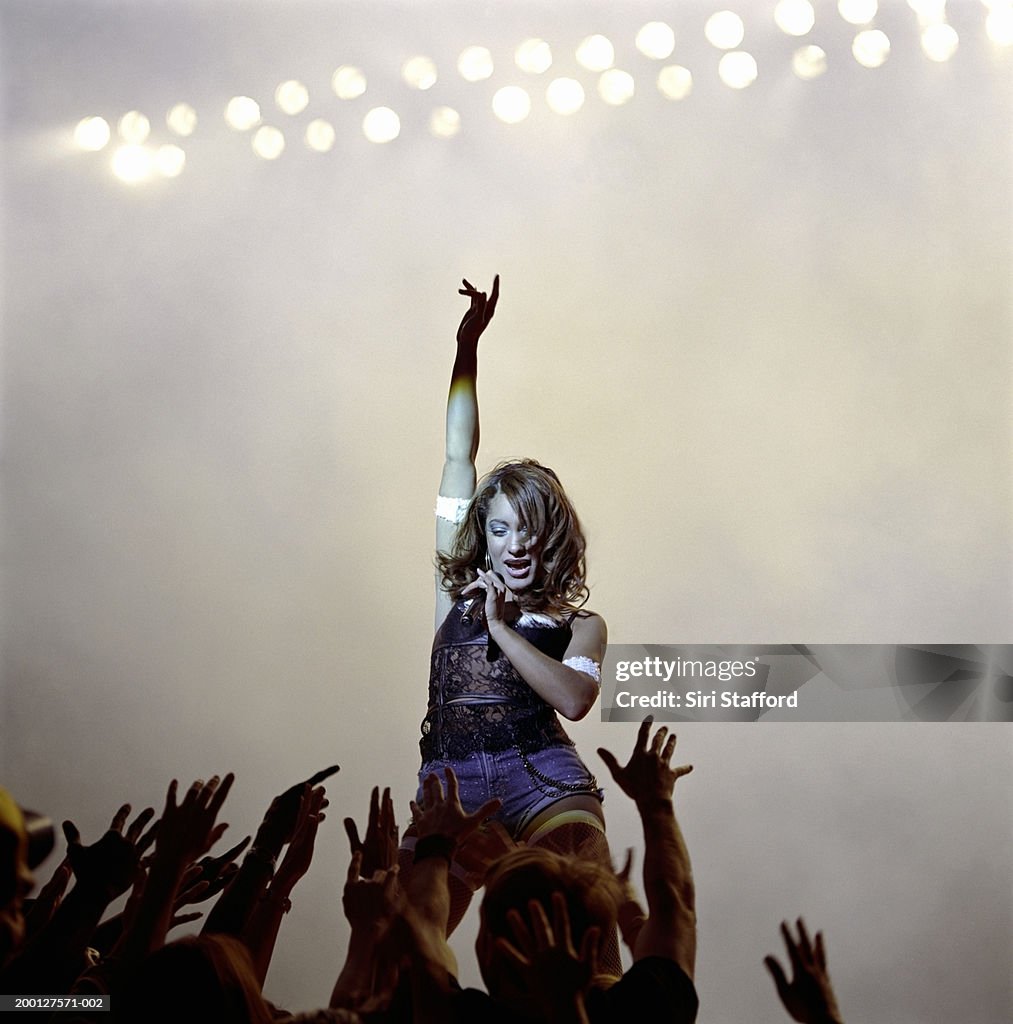 Singer looking at fans reaching toward her on stage