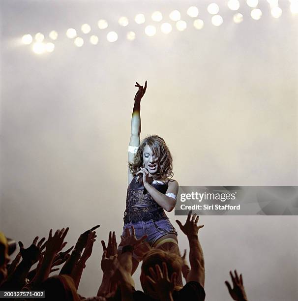 singer looking at fans reaching toward her on stage - pop musician stock pictures, royalty-free photos & images