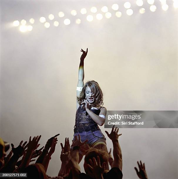singer looking at fans reaching toward her on stage - popmusik bildbanksfoton och bilder