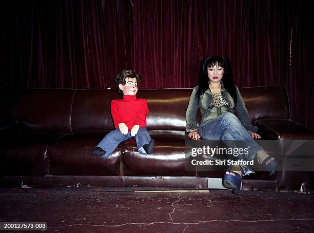 young woman sitting next to ventriloquist dummy on couch, portrait - ventriloquo foto e immagini stock