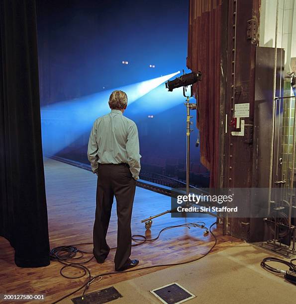 man looking at spotlights on stage, rear view - dietro le quinte concetto foto e immagini stock