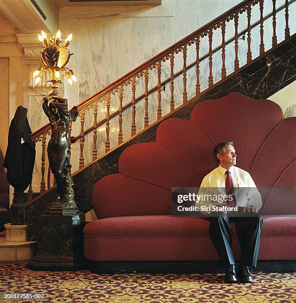 businessman sitting on couch in lobby - versierd jak stockfoto's en -beelden