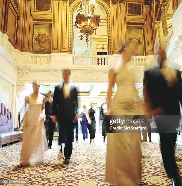 theater goers in formal attire, walking through lobby, blurred motion - woman in evening dress stock-fotos und bilder