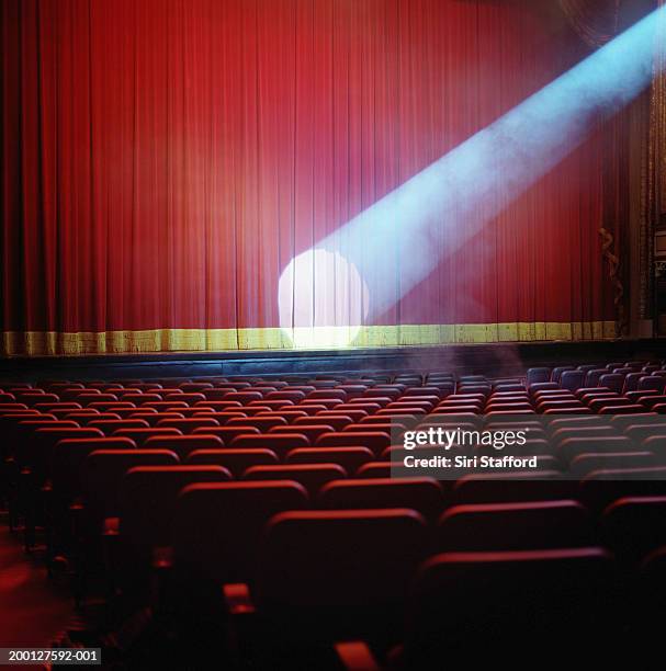 spotlight on red theater curtain - spotlicht stockfoto's en -beelden