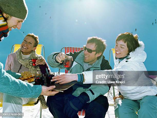 man holding tray of bread and drinks for three friends, outdoors - après ski stockfoto's en -beelden