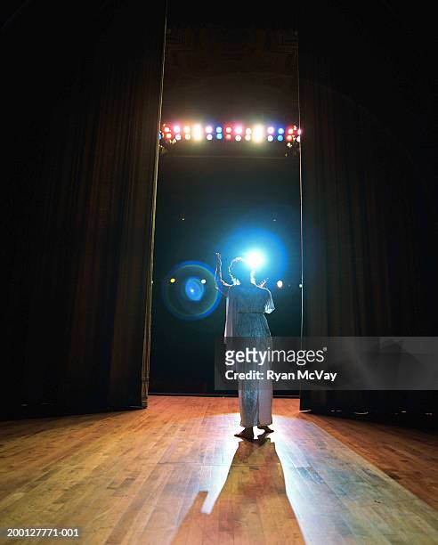 opera singer performing on stage, reaching toward spotlight, rear view - opera stage stock-fotos und bilder